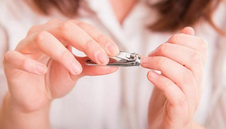 امراة تقص أظافرها وتتبع أهم نصائح العناية بالأظافر قبل العيد
